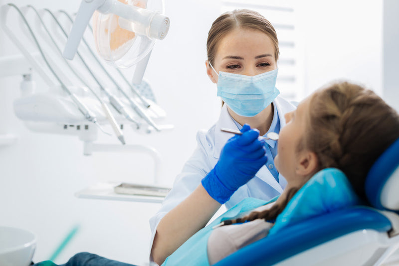 Dentist-holding-sterilized-dental-tools-while-checking-patient's-teeth